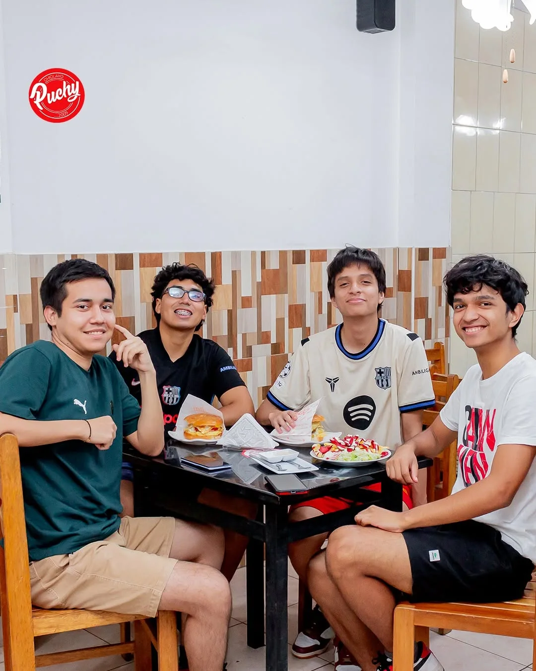 Cuatro amigos con sus hamburguesas en una mesa de Puchy